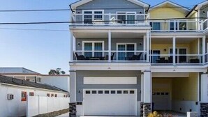 Un edificio residencial de dos plantas con un balcón en el piso superior, un garaje y cimientos de piedra.