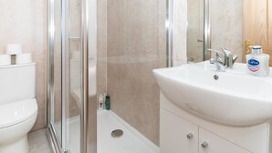 Ein modernes Badezimmer mit einer Duschkabine aus Glas, einem weißen Waschbecken und einer Toilette.