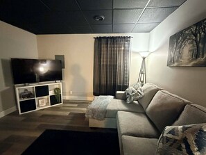 Un salon avec un canapé, une télévision et un tableau accroché au mur.