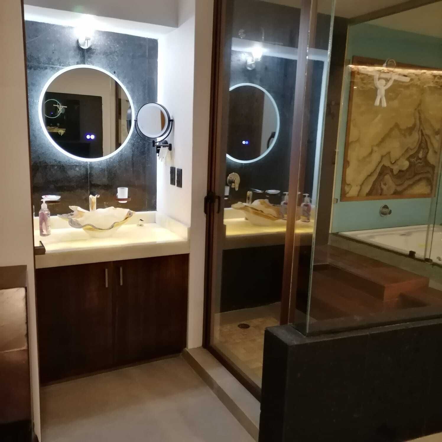 Une salle de bain moderne avec deux vasques, des miroirs ronds et un mur en marbre.