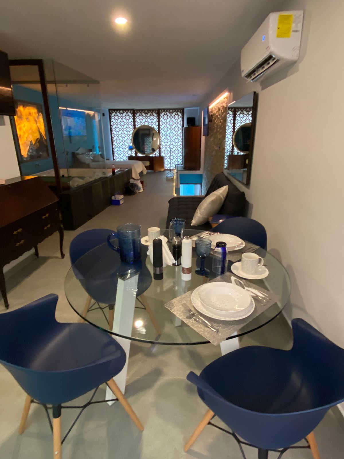 A dining area with a glass table set for two, surrounded by blue chairs.
