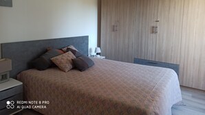 Un dormitorio con cama, mesita de noche, lámpara y armario.