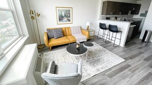 Una sala de estar moderna con un sofá, sillas, una mesa de centro y una cocina con armarios y un lavabo.