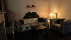 A living room with a sofa, a coffee table, and a lamp. - Gîte Coquin (Augan)