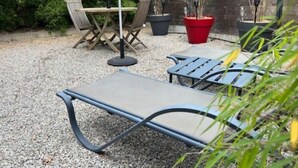 A patio area with a table and chairs, surrounded by gravel and potted plants. - Gîte Coquin (Augan)