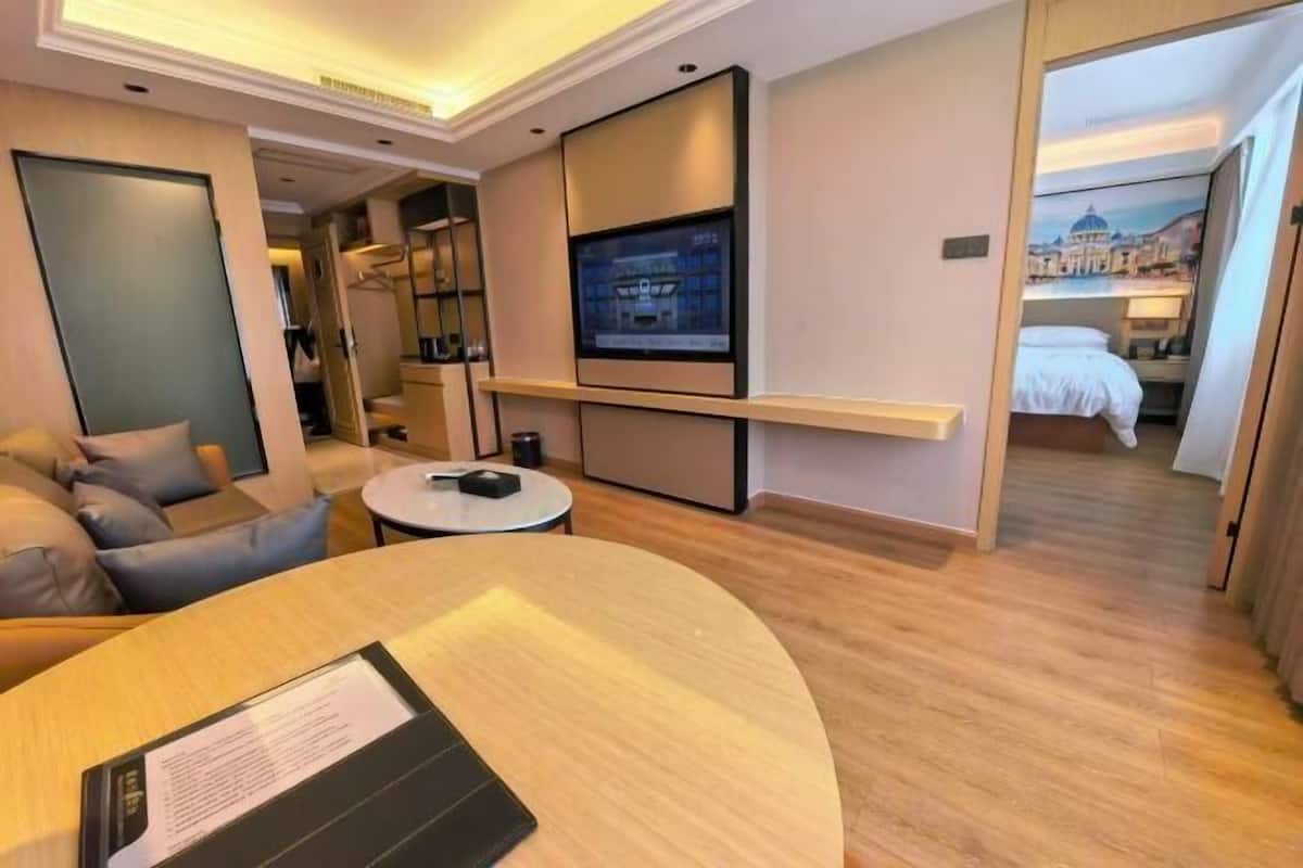 Una habitación de hotel moderna con sofá, una mesa redonda, televisor de pantalla plana y una cama con vista a la ciudad.