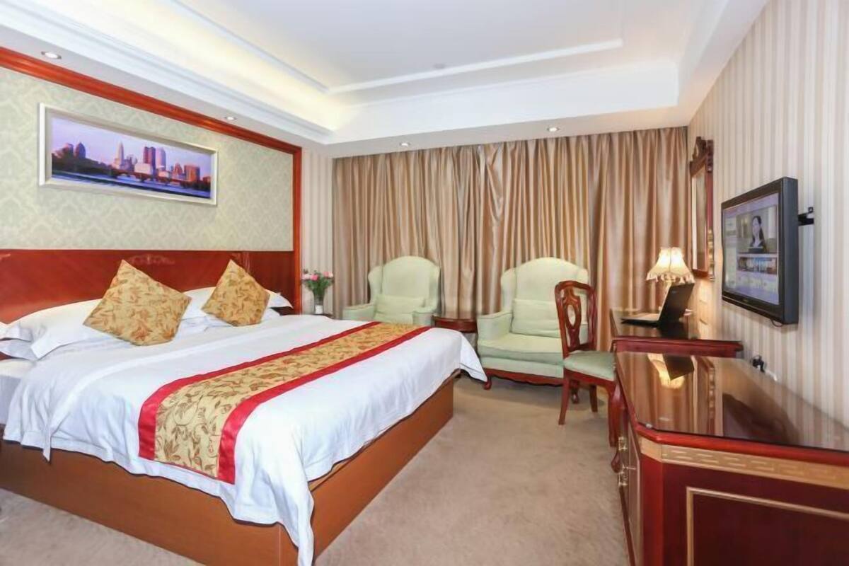 Habitación de hotel con una cama grande, un escritorio, una silla y un televisor.