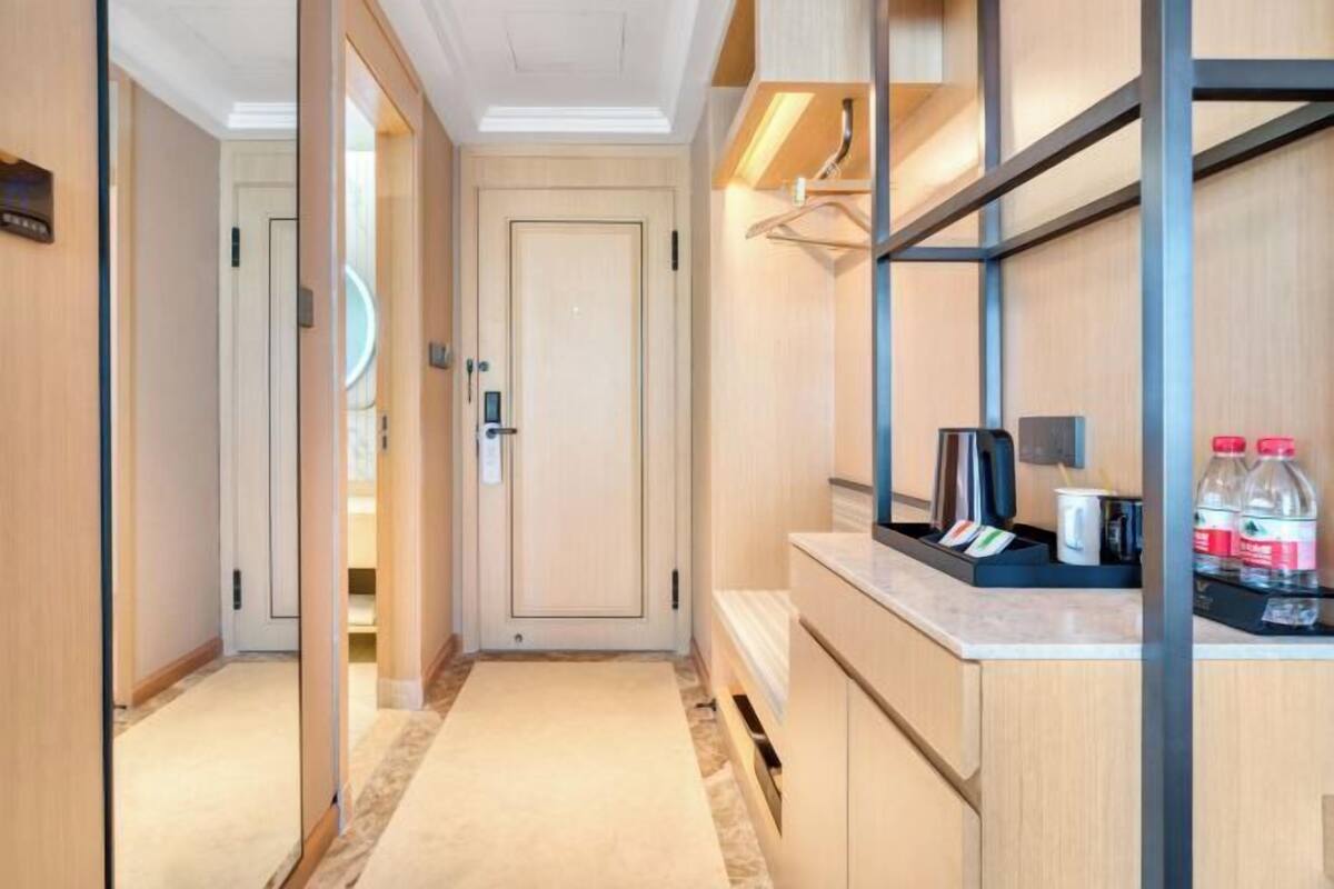 Un pasillo de hotel con una puerta, un mostrador con servicios y un perchero en la pared.