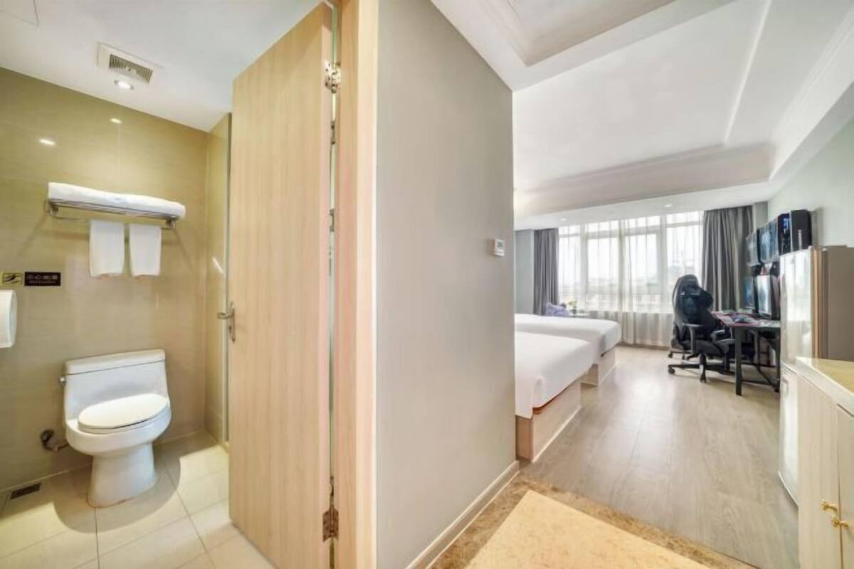 Una habitación de hotel con inodoro, cama, escritorio y televisor.
