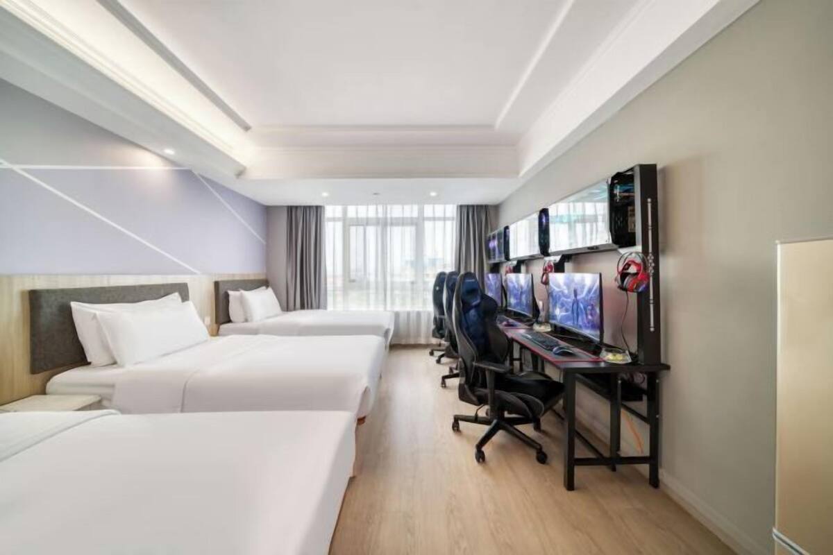 Habitación de hotel con dos camas, un escritorio con computadora y televisión.