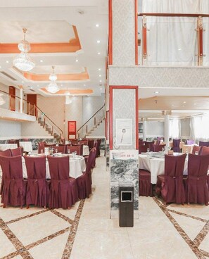A multi-level dining area with tables and chairs, a staircase, and a chandelier. - Vienna Hotel Ningbo Jiangbei Avenue Wanda Branch (Ningbo)