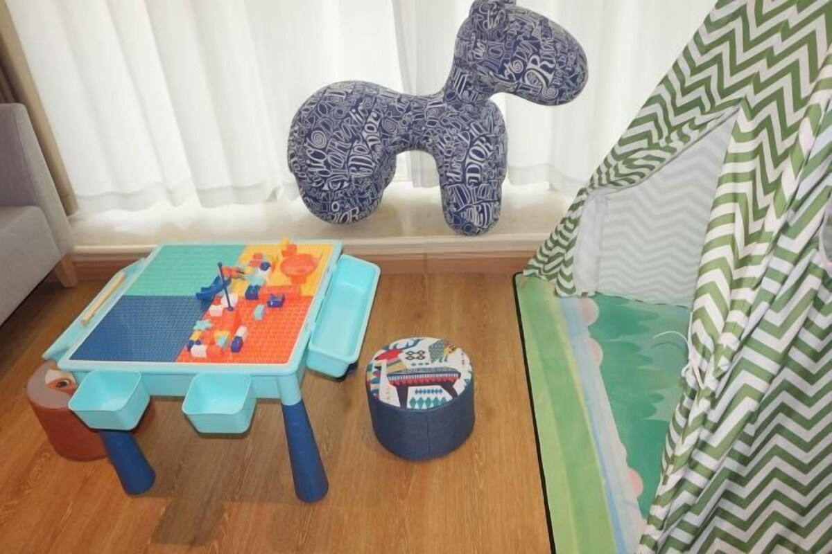 A play area with a puzzle mat, a toy horse, and a cushion with a chevron pattern.
