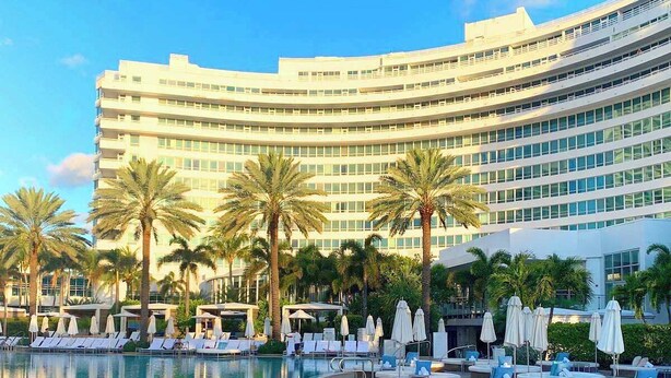 A hotel with a large pool, palm trees, and a modern building with multiple floors. - Fontain Miami Beach - Bayview Condo - We Host (Miami Beach)