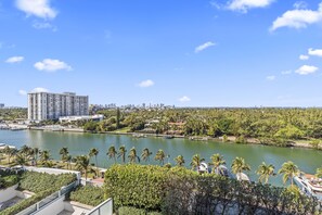 A waterfront hotel with a view of the city skyline, palm trees, and a marina.
