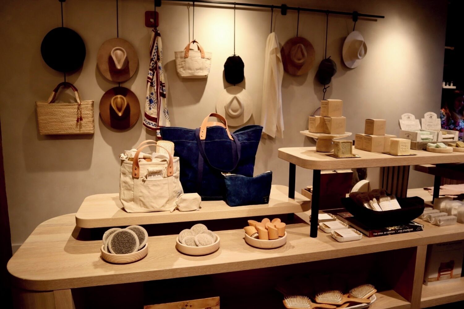 Exhibición en tienda con diferentes bolsos, sombreros y artículos de aseo.
