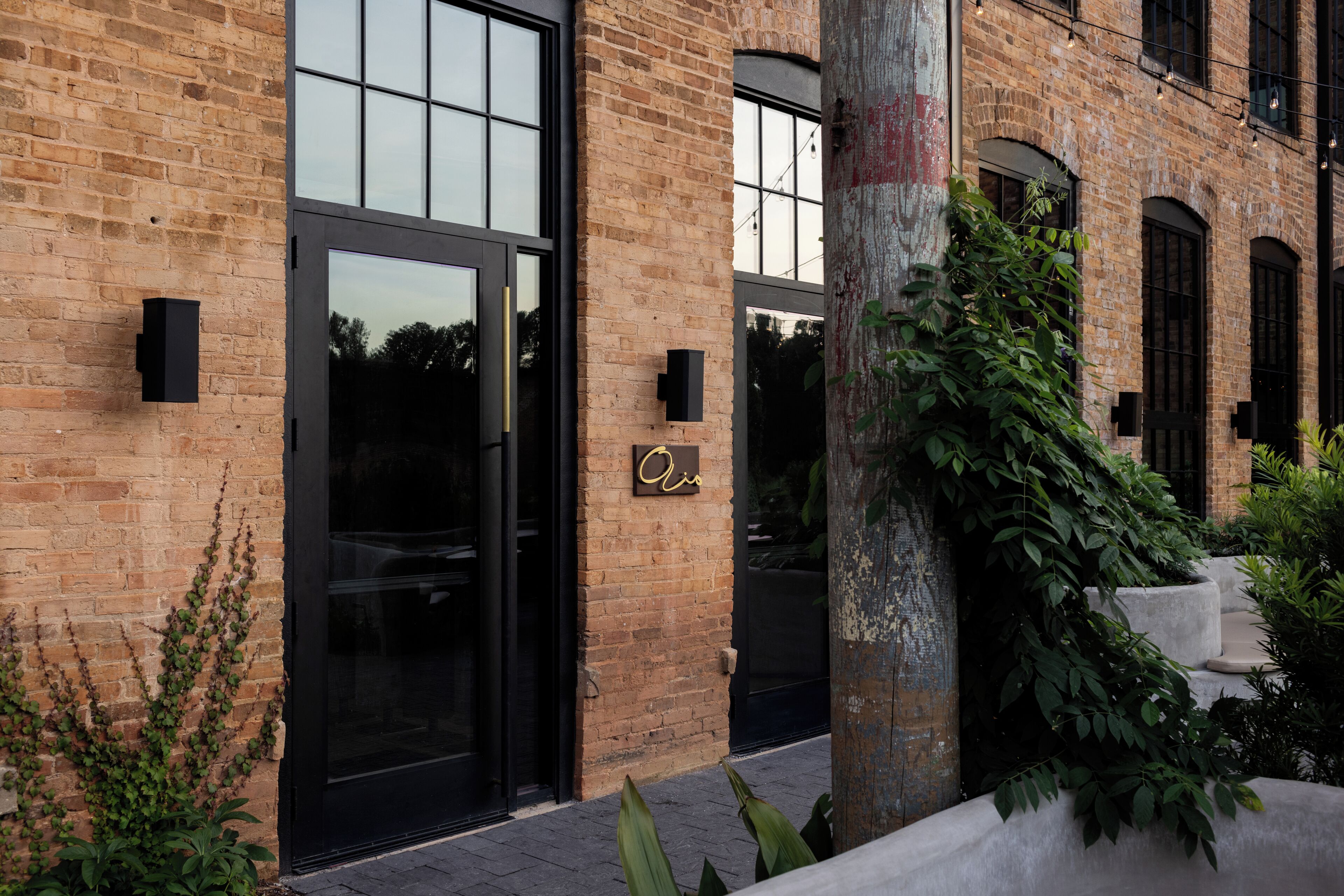 A brick building with large windows and a black door.