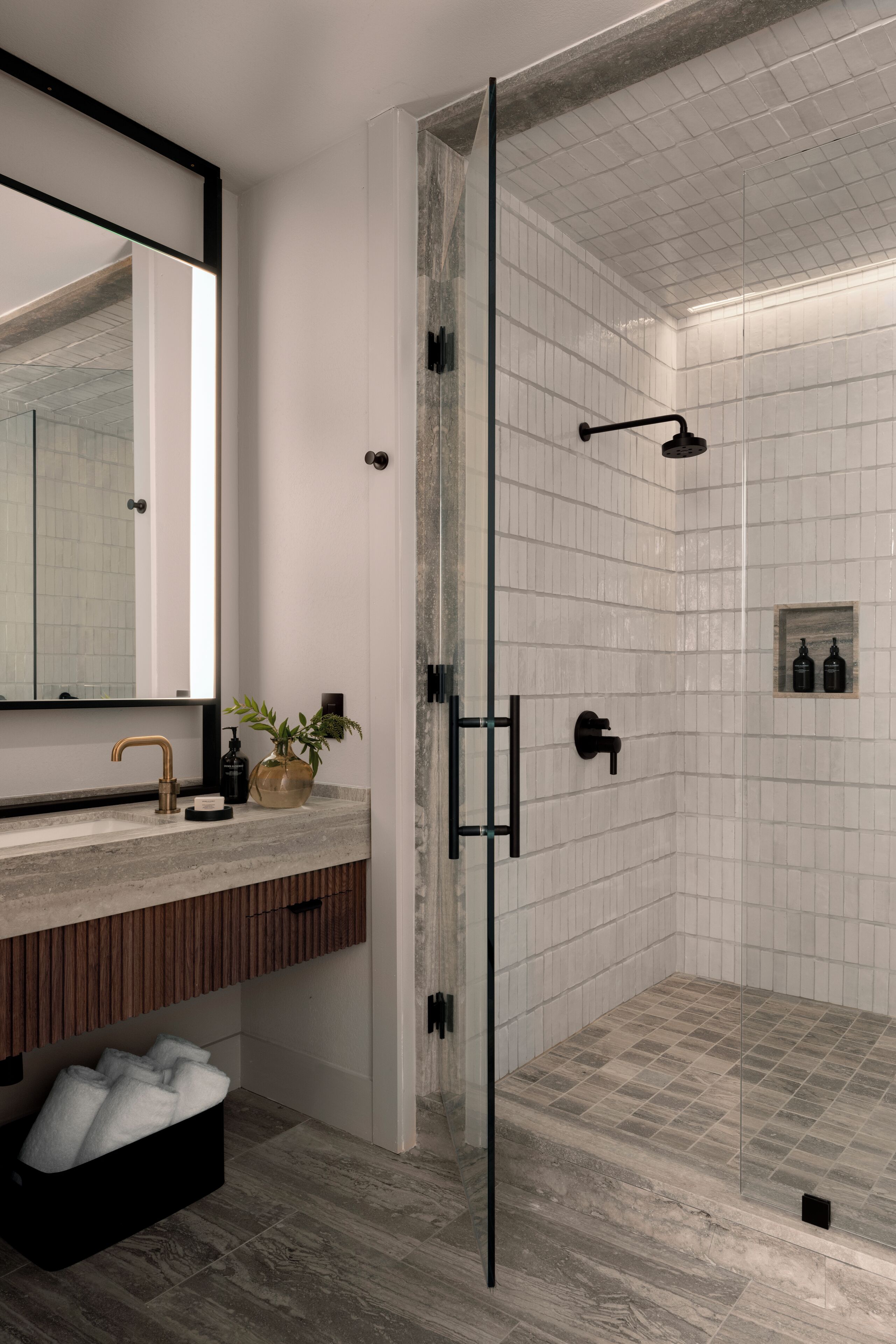 A modern bathroom with a glass shower enclosure, a wooden vanity, and a large mirror.