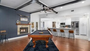 A modern kitchen with white cabinets, stainless steel appliances, and a central island with bar stools. - Lone Star house  by AT&T, Six Flags ,Globe life,Pool-Jacuzzi! (Grand Prairie)
