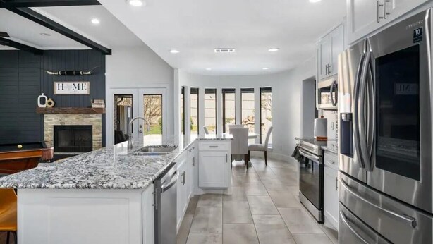 A modern kitchen with granite countertops, stainless steel appliances, and a central island. - Lone Star house  by AT&T, Six Flags ,Globe life,Pool-Jacuzzi! (Grand Prairie)