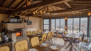 A dining area with a fireplace, wooden beams, and a view of the city. - Theodora Village  (Ürgüp)