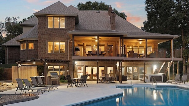 Une maison à deux étages dotée d’une piscine, d’un espace salon extérieur et d’une terrasse couverte.