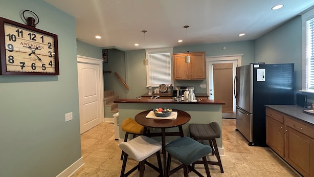 A kitchen with a dining area, featuring a clock, a refrigerator, and a coffee maker. - Cozy Derby Home
2 Bedroom Shotgun style home, with Large Adorable Loft (Louisville)