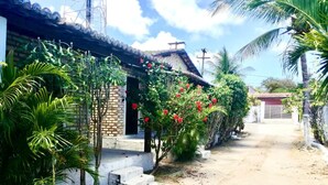 A residential area with a house featuring a brick facade, a concrete staircase, and a small porch. - CHALÉS CENTRO DA PIPA (Tibau do Sul)