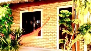 A brick house with a wooden door, a small window, and a hammock. - CHALÉS CENTRO DA PIPA (Tibau do Sul)