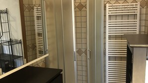A bathroom with a glass shower enclosure, a black vanity, and a tiled floor. - 1 Bedroom Cottage in Verzi (Verzi)