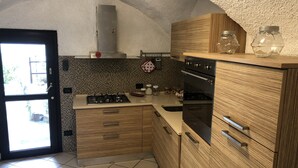 A kitchen with wooden cabinets, a gas stove, and a built-in oven. - 1 Bedroom Cottage in Verzi (Verzi)