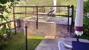 A rooftop terrace with a view of a mountainous landscape, a metal railing, and a white umbrella. - 1 Bedroom Cottage in Verzi (Verzi)