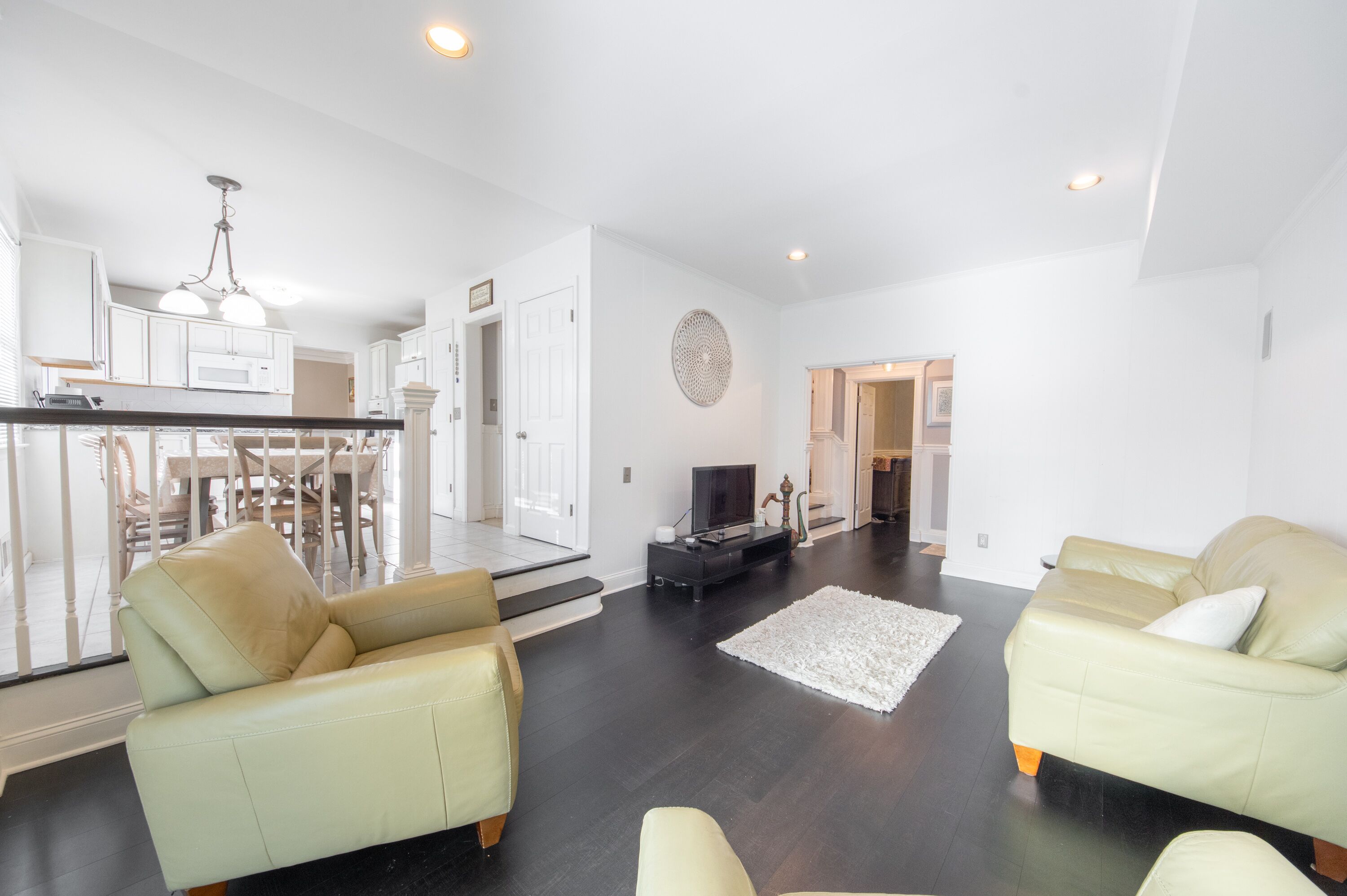 A modern living room with a sofa, a TV, and a dining area with chairs and a table.