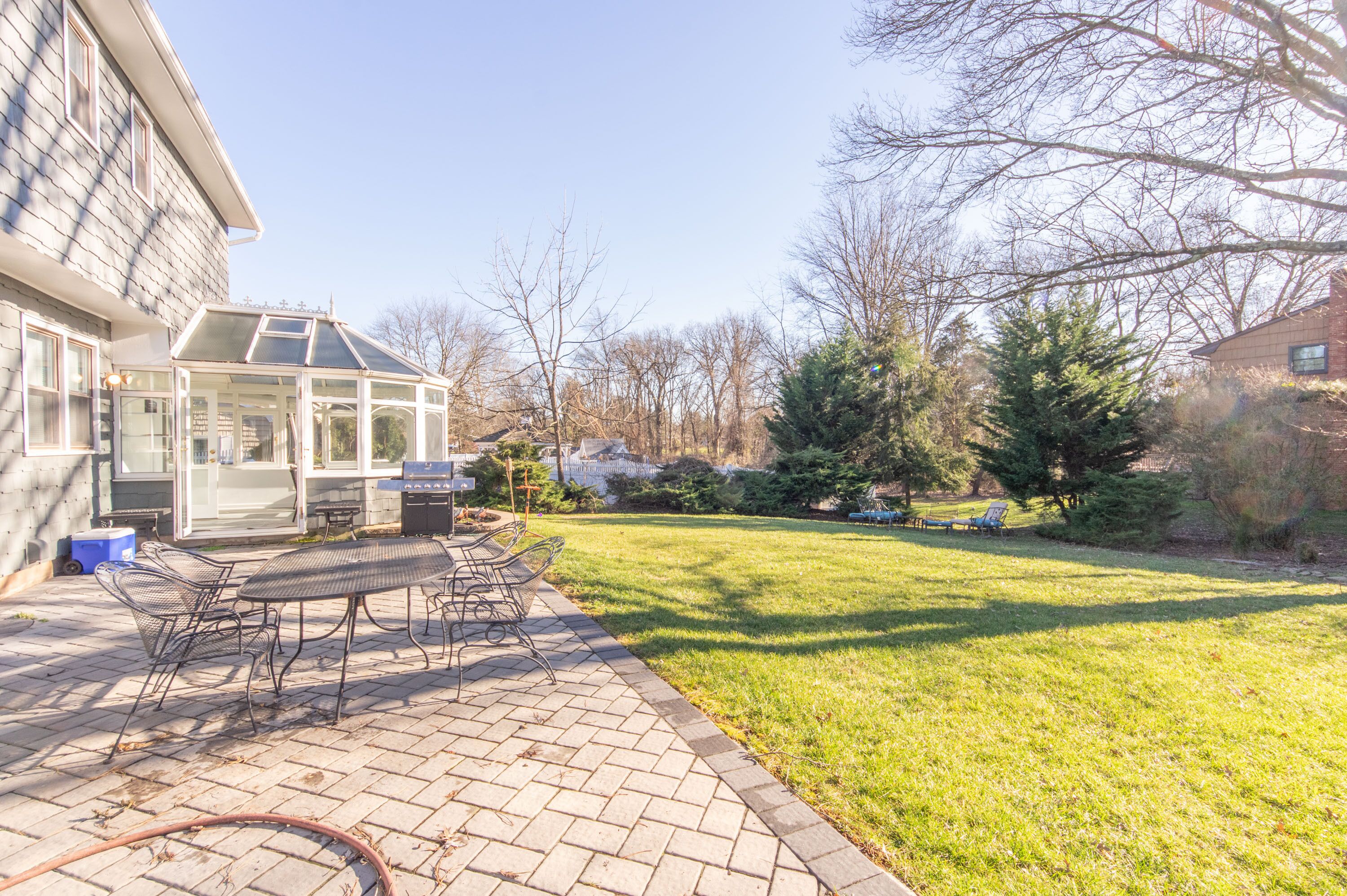 A patio with a glass enclosure, outdoor seating, and a grassy lawn.