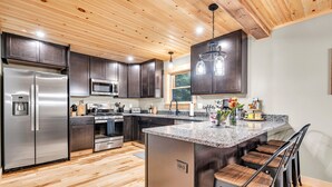 A modern kitchen with stainless steel appliances, dark wood cabinets, and a granite countertop.