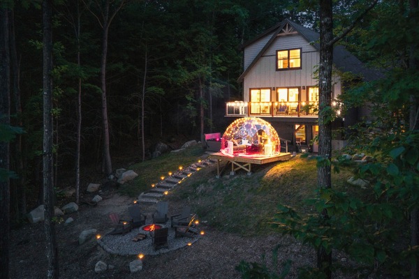 A serene backyard at night with an all-season dome, fire pit, and hot tub.