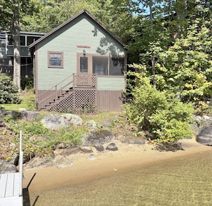 Une cabane dotée d’une terrasse en bois, d’un escalier et offrant une vue sur une étendue d’eau.