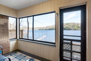 A room with a large window offering a view of a lake and forest. - Loon Lodge - Waterfront Cabin (Holderness)
