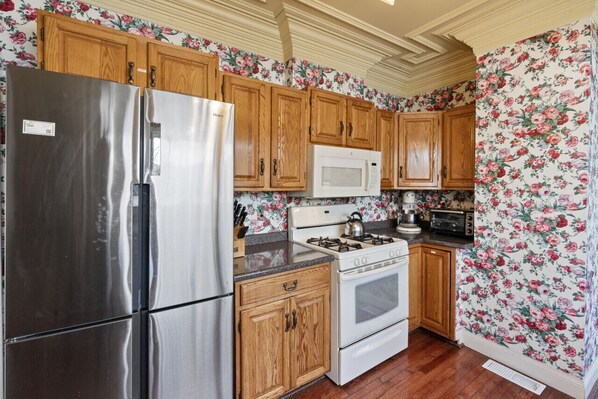 A kitchen with wooden cabinets, a stainless steel refrigerator, a white stove, and a microwave. - Waterfront home on Squam Lake (Holderness)