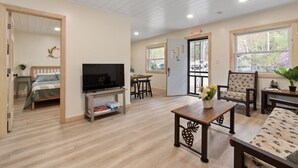 A spacious living area with a television, seating, and a door leading to another room. - Waterfront 3 bed/3 bath on Squam (#1) (Holderness)
