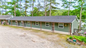 A motel with a long, single-story structure, multiple rooms, and a small porch area. - Waterfront 3 bed/3 bath on Squam (#1) (Holderness)