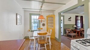 A dining area with a table and chairs, a window, and a door with a decorative panel. - Moose Manor- Squam Waterfront (Holderness)