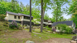 A residential area with houses, a dirt path, and surrounding greenery. - Moose Manor- Squam Waterfront (Holderness)