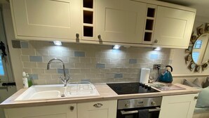Una cocina moderna con gabinetes blancos, un lavamanos doble, una estufa y un microondas.