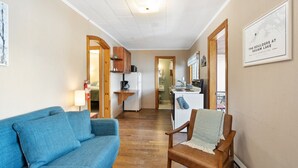 Ein gemütlicher Wohnbereich mit Sofa, Sessel, Küchenzeile und einer gerahmten Karte an der Wand.