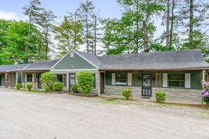 A row of two-story buildings with a gravel driveway, surrounded by trees.