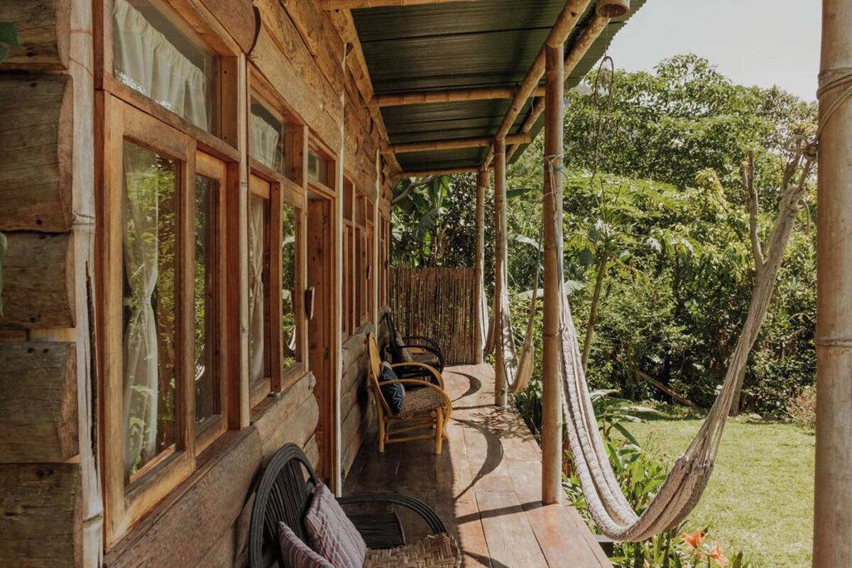Een houten gebouw met een overdekte veranda, grote ramen en een hangmat.