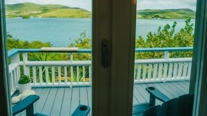 A view from a room with a door leading to a balcony overlooking a body of water and hills. - AMAZING Ensenada Honda View @ MAREA 1-1 - Punta Aloe #3 (Culebra)