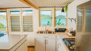 A kitchen with wooden flooring, white cabinets, a large island, a stove, and windows with a view of the outdoors. - AMAZING Ensenada Honda View @ MAREA 1-1 - Punta Aloe #3 (Culebra)