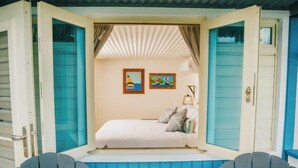 A cozy room with a bed, two chairs, a small table, and a window with curtains. - AMAZING Ensenada Honda View @ MAREA 1-1 - Punta Aloe #3 (Culebra)