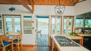 A kitchen with a gas stove, wooden cabinets, and a view of the lake. - AMAZING Ensenada Honda View @ MAREA 2-2 - Punta Aloe #3 (Culebra)